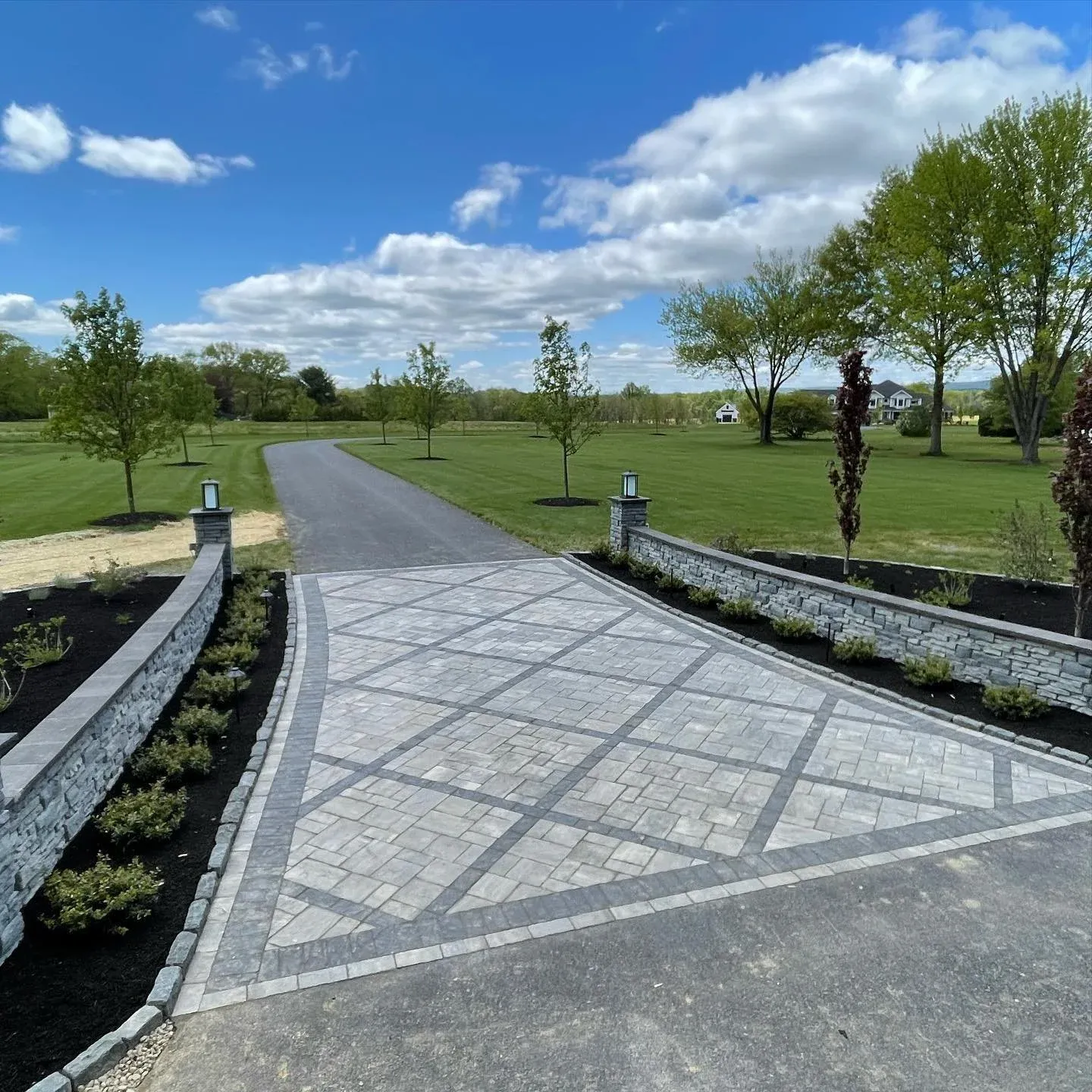 Long driveway with decorative diamond paver inlay and stone entrance walls