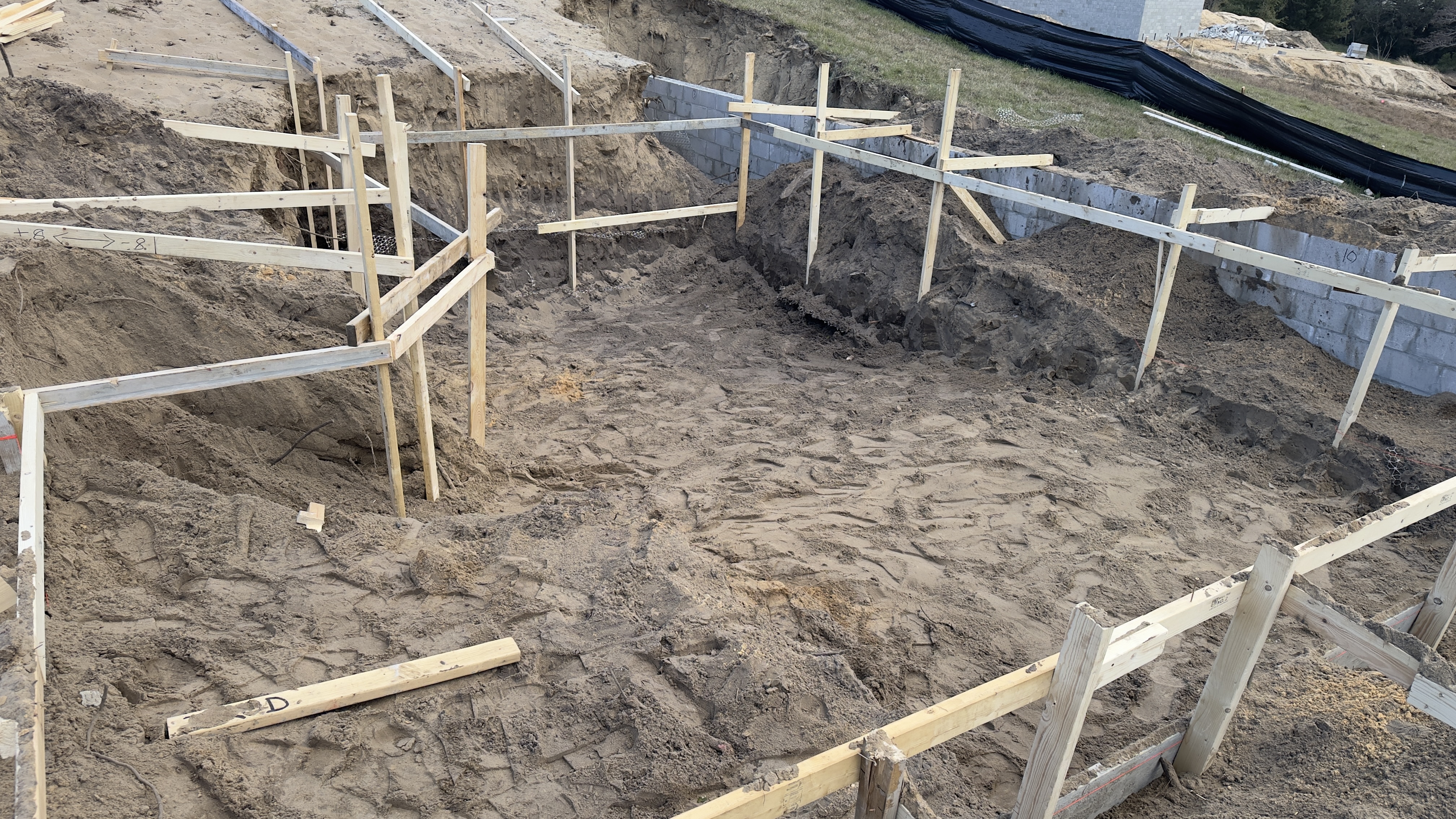 Pool layout marked with wood stakes and string during the design phase