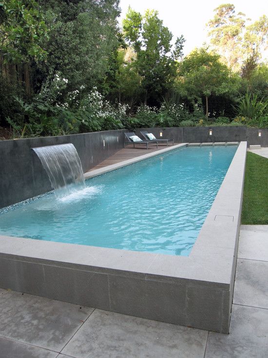 Wood lounge deck beside a custom pool with waterfall