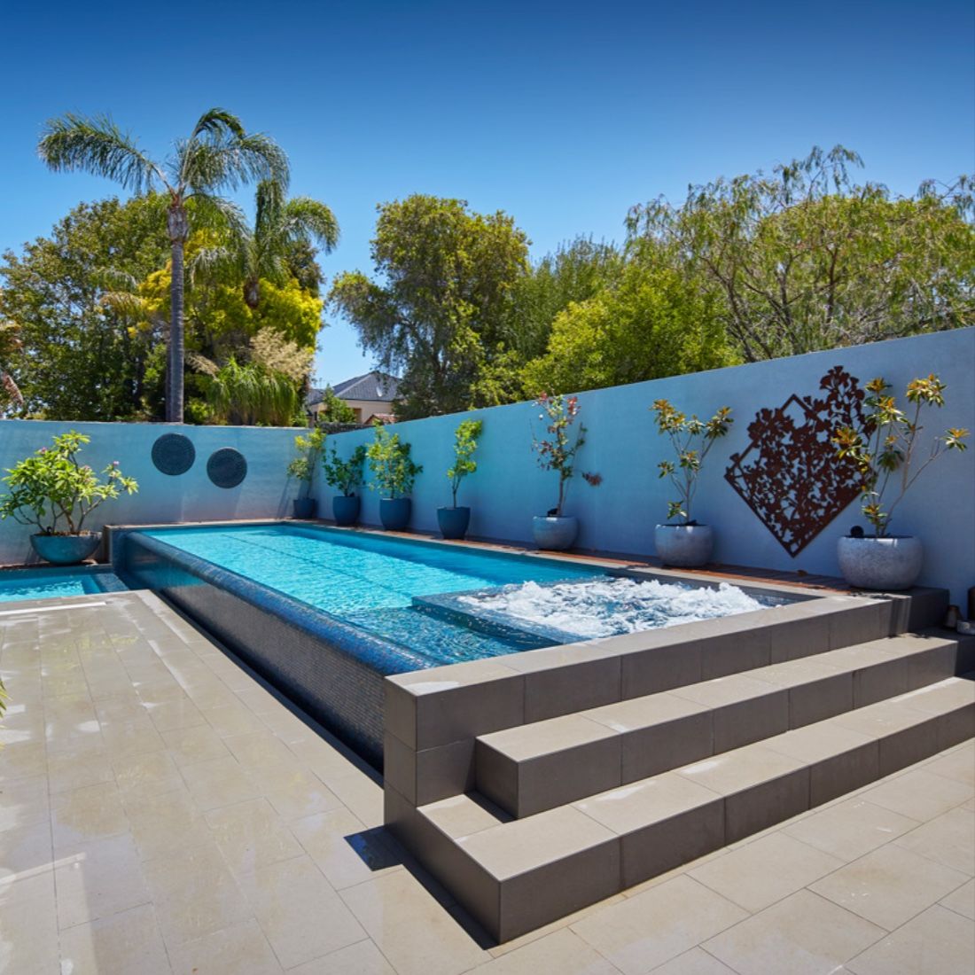 Pool and spa combo with steps and a modern accent wall