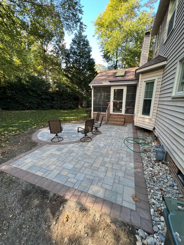 Simple paver patio behind a house with seating area