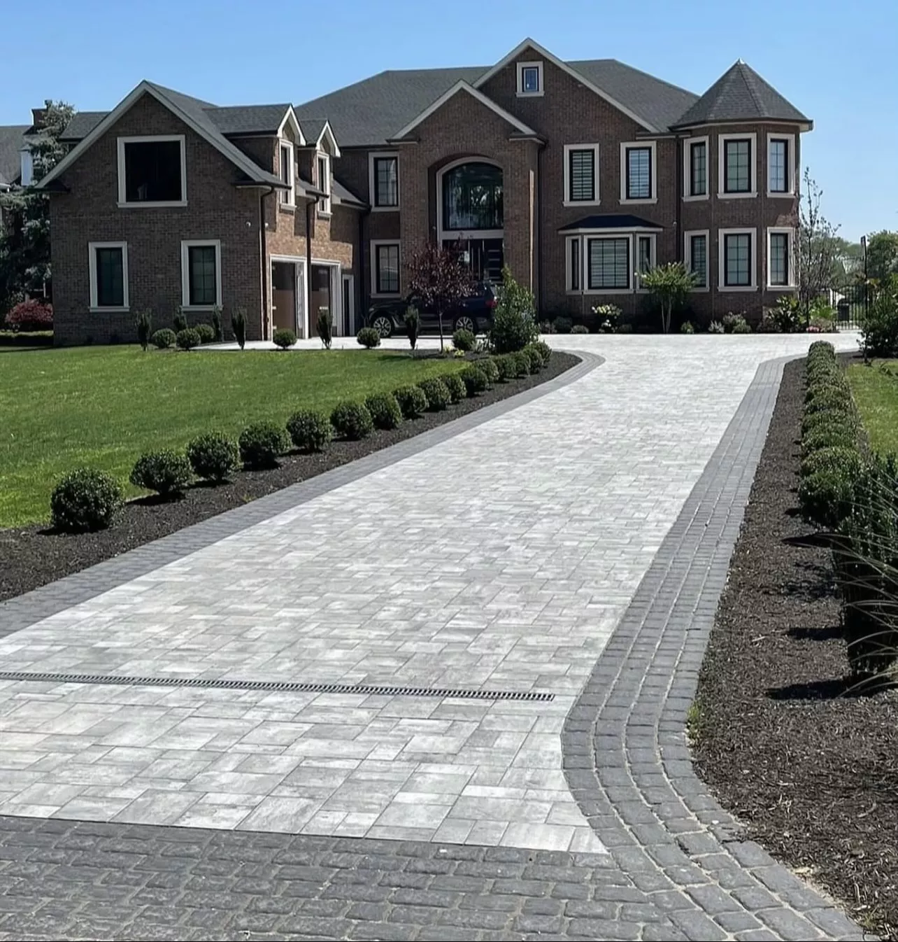 Elegant paver driveway leading to a brick home