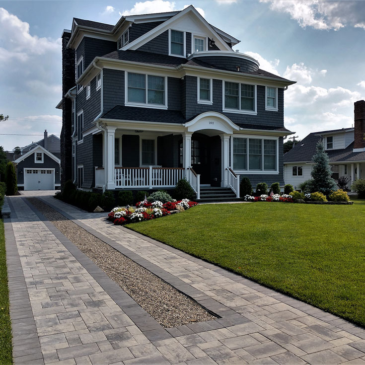 Driveway with center gravel strip leading to a two-story home
